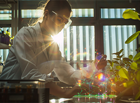 Eine Wissenschaftlerin in einem Labor, die eine leuchtende, mit Datenpunkten überzogene Probe betrachtet, im Hintergrund Pflanzen und das durchs Fenster einfallende Sonnenlicht, das ein Flair von Innovation und Forschung vermittelt.